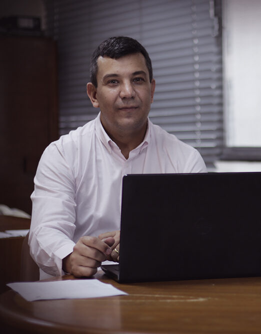 Os sócios Renato e Rodrigo, em frente a uma mesa com computador e outros objetos.